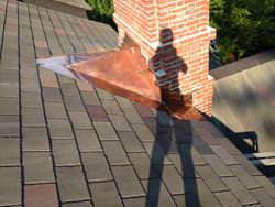 Custom copper cricket chimney installation with step flashing